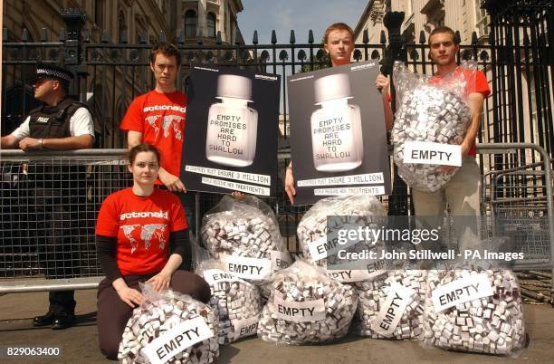 Group of protesters from Action Aid stand outside the gates of Downing Street, with bags of empty pill bottles calling on the Prime Minister to pay...