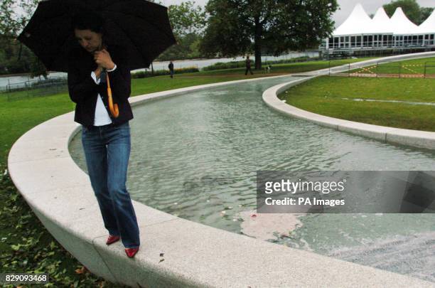 Member of the public shelters on the The Princess Diana Memorial Fountain, after it flooded the day after it was officially opened by the Queen....