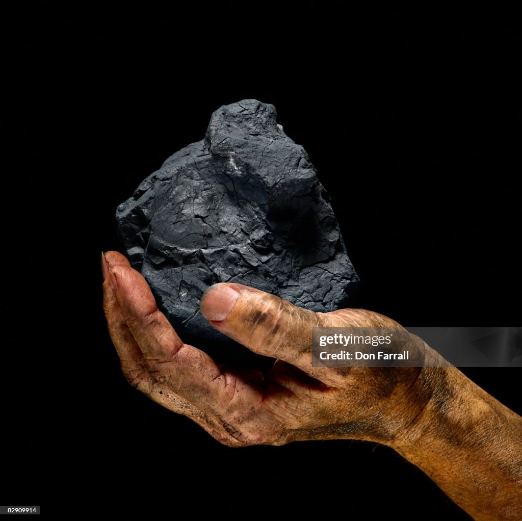 Chunk of coal in a dirty hand