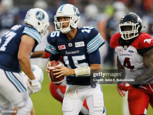 Ricky Ray of the Toronto Argonauts rolls Out to pass with Micah Johnson of the Calgary Stampeders in pursuit during a CFL game at BMO Field on August...