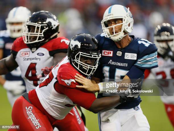 Ricky Ray of the Toronto Argonauts is hit by Derek Wiggan of the Calgary Stampeders after throwing a pass during a CFL game at BMO Field on August 3,...