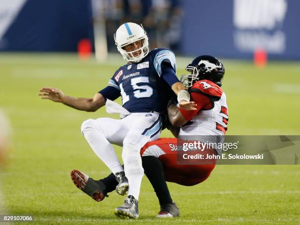 Ricky Ray of the Toronto Argonauts is tackled by Charleston Hughes of the Calgary Stampeders during a CFL game at BMO Field on August 3, 2017 in...