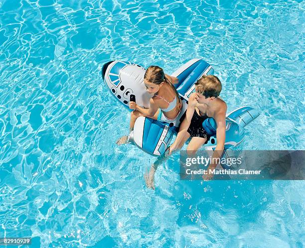 boy and girl ride on a float in a pool - inflatable airplane stock pictures, royalty-free photos & images