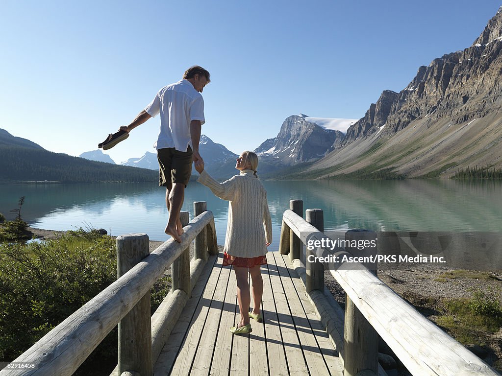 Man balancing from bridge with woman, Bow Lake