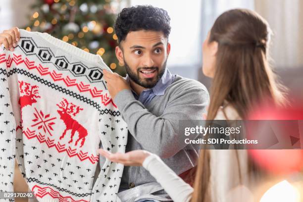 面白い表現で男はクリスマスのセーターを保持します。 - 醜さ ストックフォトと画像