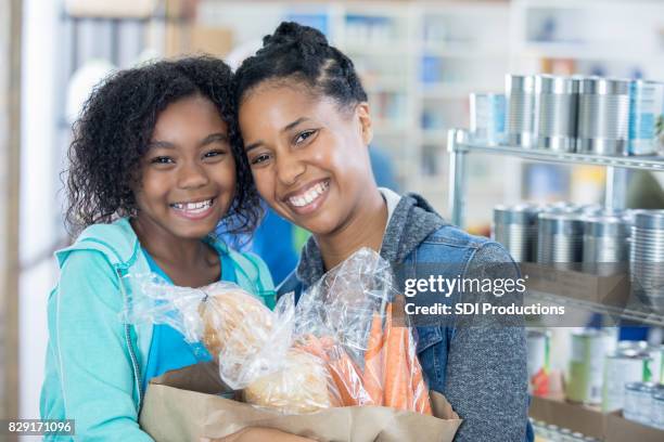 cute little girl and her mom donate groceries to food bank - banco alimentar imagens e fotografias de stock