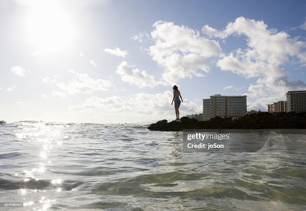 Woman standing on rocks near ocean