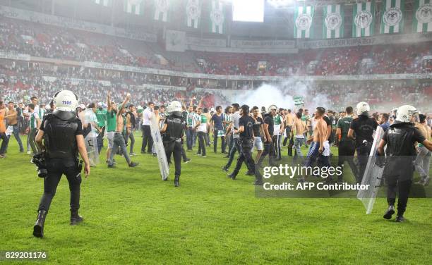 Turkish anti-riot police officers react as football fans invade the pitch during the Turkish Super Cup final football match between Besiktas and...