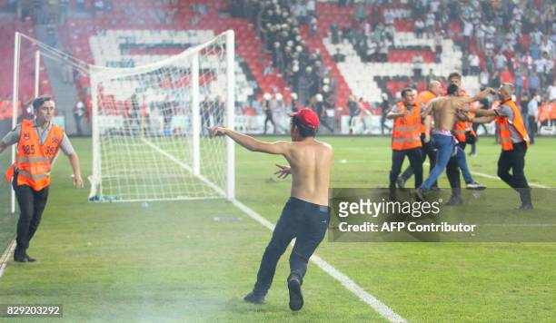 Turkish security officers try to detain football fans invading the pitch during the Turkish Super Cup final football match between Besiktas and...