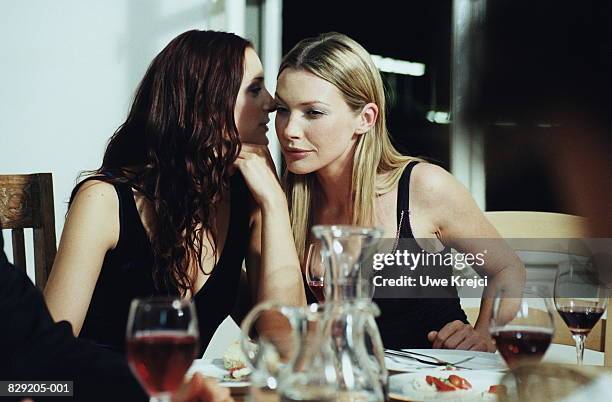 two young women talking at dinner party - fluisteren stockfoto's en -beelden