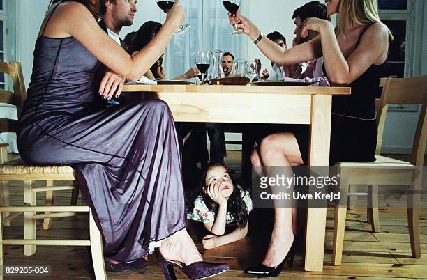 girl (7-9) lying under dining table, group of adults at table - six under �ストックフォトと画像