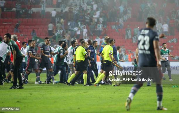 Besiktas' Portuguese defender Pepe and Brazilian defender Adriano leave the pitch with referees as football fans invade the pitch during the Turkish...
