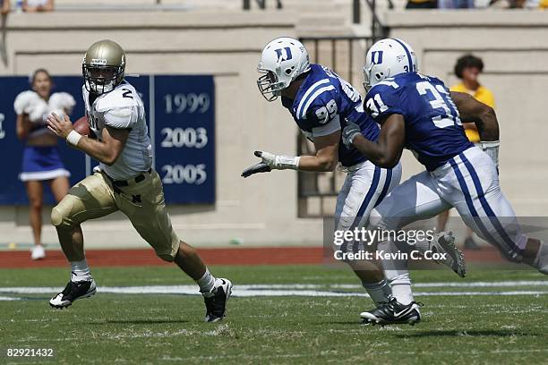 Jarod Bryant of the Navy Midshipmen runs with the ball against Wesley Oglesby and Vincent Rey of the Duke Blue Devils during the game at Wallace Wade...