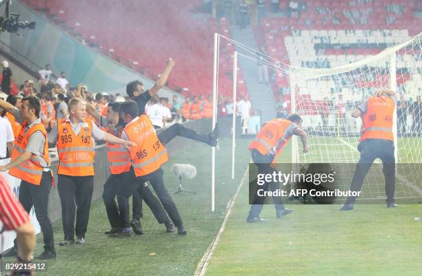 Turkish security officers try to detain football fans invading the pitch during the Turkish Super Cup final football match between Besiktas and...