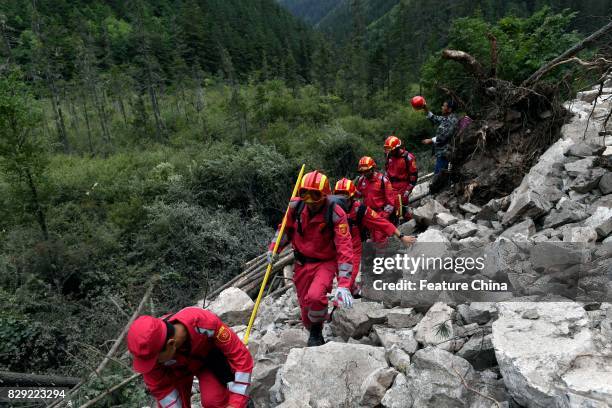 Rescuers climb over a landslide caused by the powerful earthquake on August 10, 2017 in Jiuzhaigou, China. PHOTOGRAPH BY Feature China /