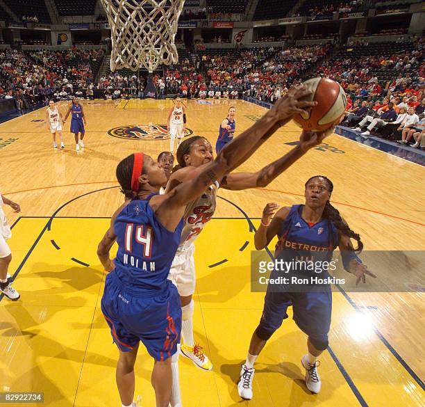 Tamika Catchings of the Indiana Fever battles Deanna Nolan and Taj McWilliams-Franklin of the Detroit Shock in Game One of the Eastern Conference...