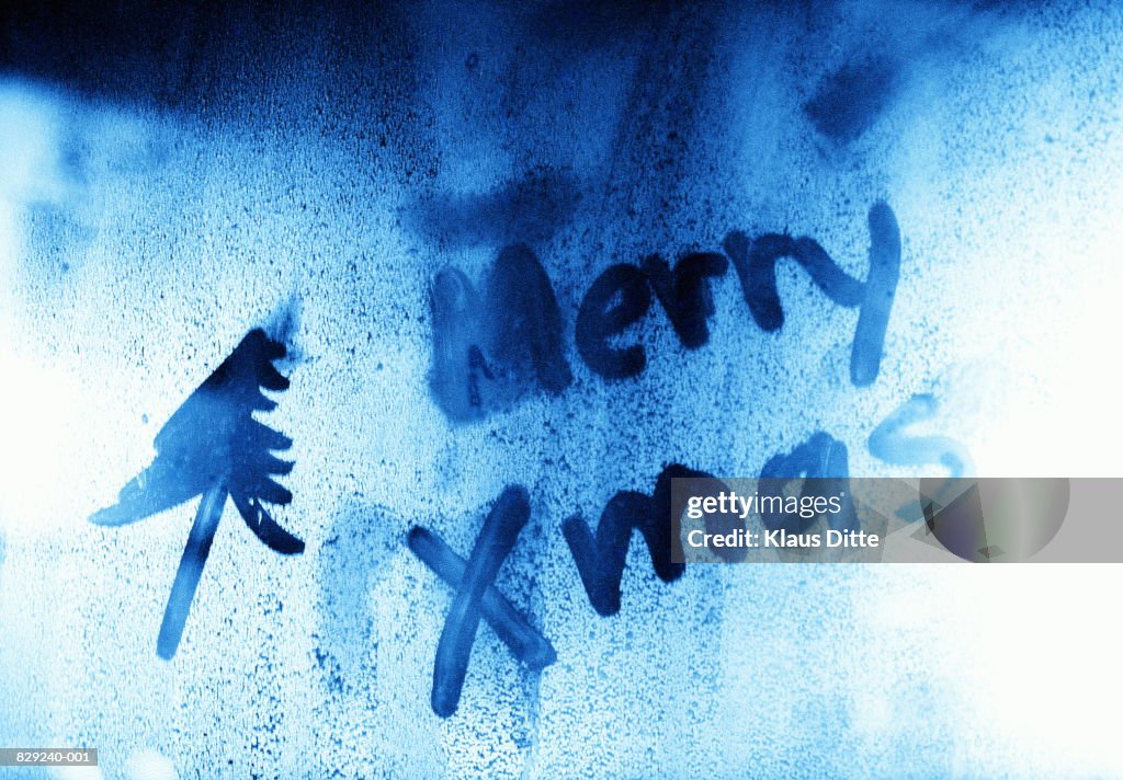 Words 'Merry Christmas' written in frost on window (toned B&W)