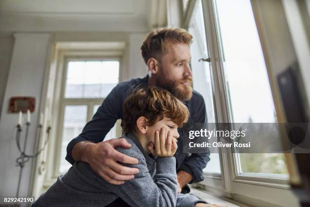 serious father and son looking out of window - leanincollection father photos et images de collection