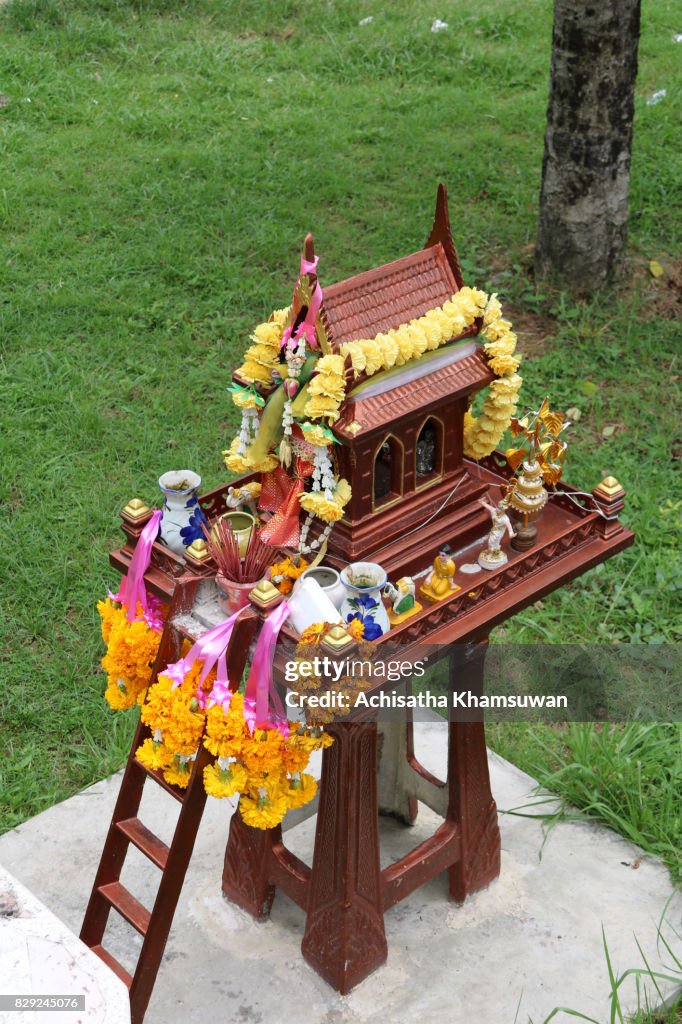 Thai Geisterhaus in dunkelrot auf grünen Rasen Hintergrund.