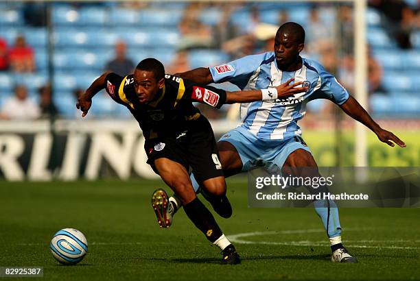 Dexter Blackstock of QPR tries to hold off the challenge of Isaac Osbourne of Coventry during the Coca-Cola Championship match between Coventry City...