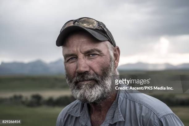 portrait of rancher, with range and mountains behind - beard stock pictures, royalty-free photos & images