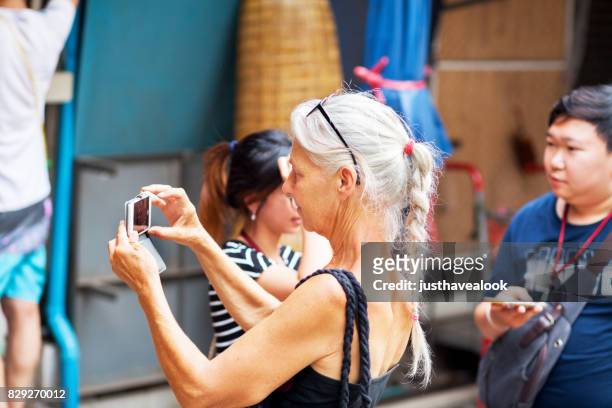mature caucasian woman and tourist with mobile - plat thai stock pictures, royalty-free photos & images