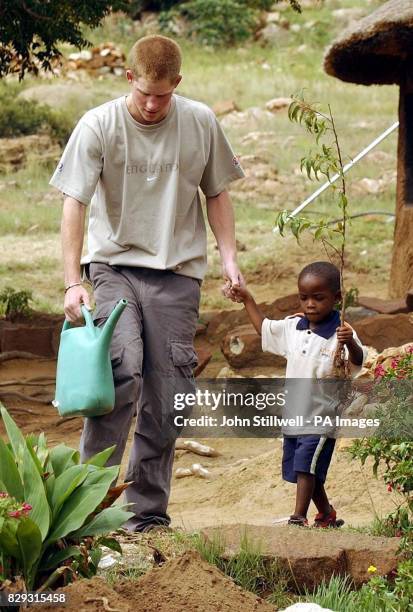 Prince Harry planting a tree with young orphan Mutsu Potsane at the Mants'ase Children's Home for children orphaned by and suffering from Aids near...