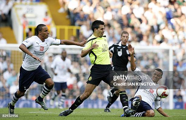 Wigan Athletic's Austrian player Paul Scharner is challenged by Tottenham's Jermaine Jenas also under pressure from Tottenham's Cameroon player...