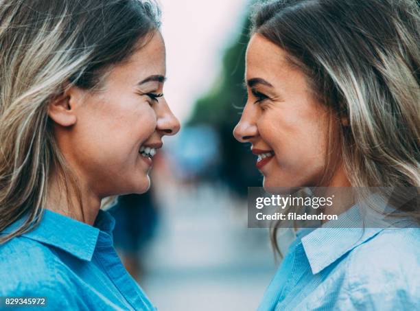 twins staande van aangezicht tot aangezicht - eeneiige tweeling stockfoto's en -beelden