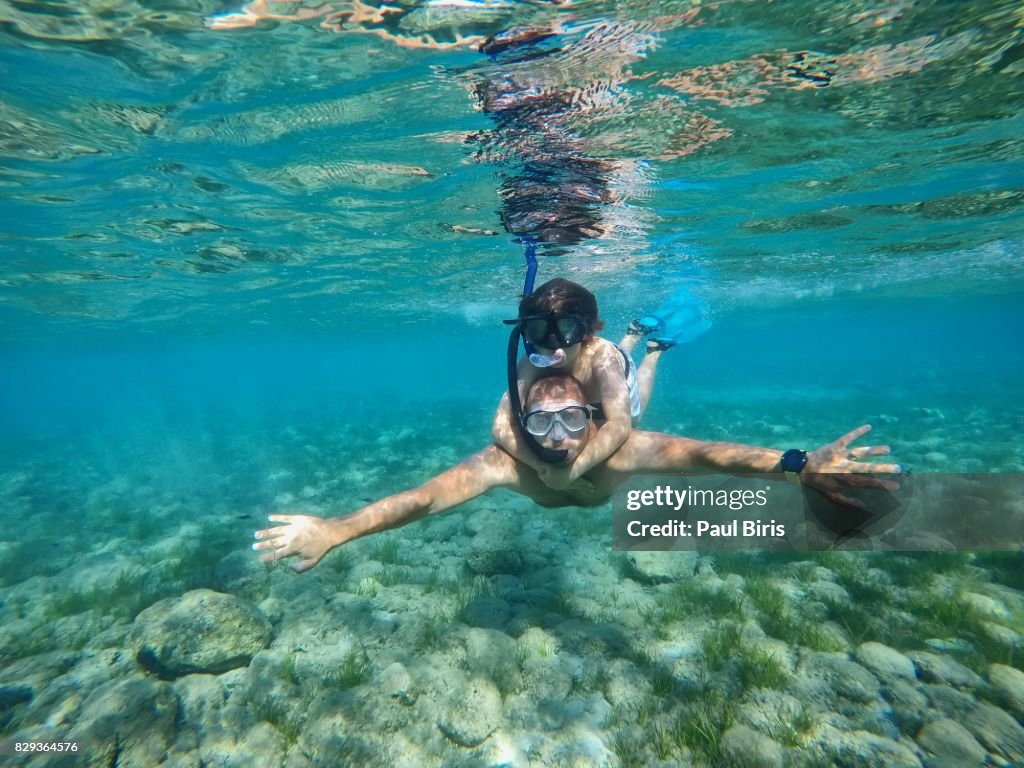 Father and son snorkeling in sea, Zakynthos Island, Greece