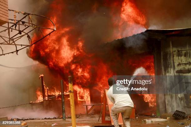 Local man tries to extinguish fire caused by supporters of the opposition candidate Raila Odinga during a demonstration against the election results...