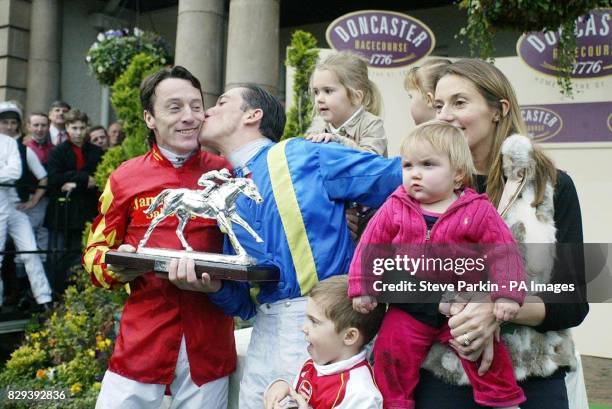 Jockey Frankie Dettori kisses fellow jockey Kieren Fallon after receiving the Jockey Championship trophy as his wife Catherine and children look on,...