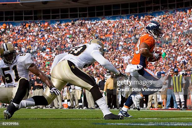 Michael Pittman of the Denver Broncos scores a touchdown Jonathan Villma and Marvin Mitchell both of the New Orleans Saints at Invesco Field at Mile...