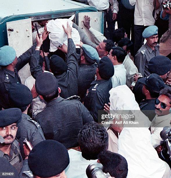 Police help Ahmed Omar Saeed Sheikh from an armed car as he and two other suspects are escorted February 25, 2002 to a court in Karachi, Pakistan. A...