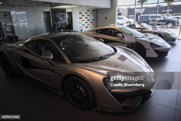 Blade silver 2017 McLaren Automotive Ltd. 570GT, left, and white 570S coupe vehicles are displayed inside the McLaren Newport Beach dealership in...