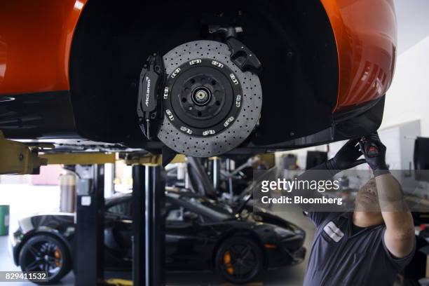 Mechanic performs a maintenance service on a McLaren Automotive Ltd. 650S vehicle at the McLaren Newport Beach service center in Costa Mesa,...