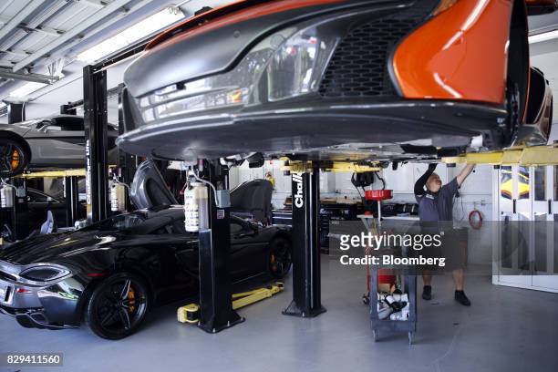 Mechanic performs a maintenance service on a McLaren Automotive Ltd. 650S vehicle, right, at the McLaren Newport Beach service center in Costa Mesa,...