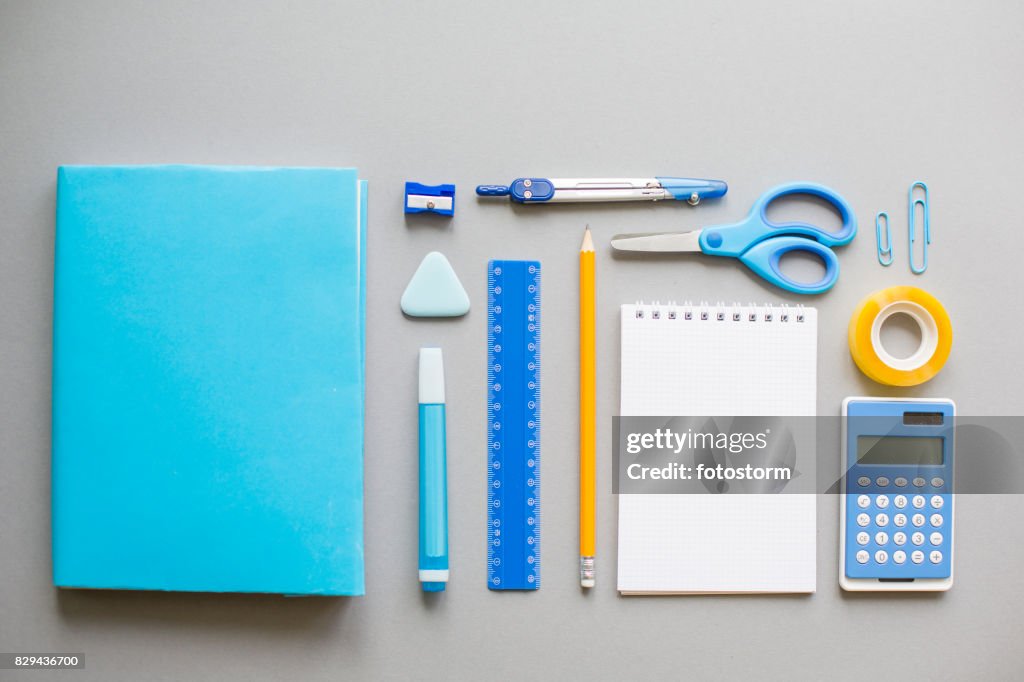 Blue school supplies on grey background