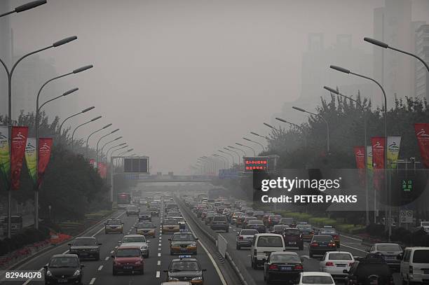 Cars drive through thick smog on a street in Beijing on September 21 the first day of no traffic restrictions which limited motorists with even or...