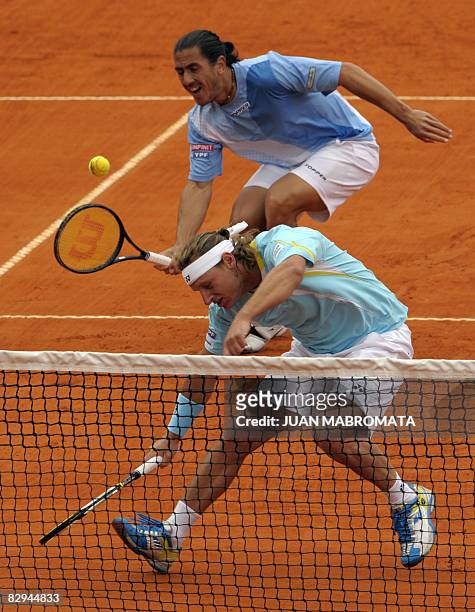 Argentina's tennis player David Nalbandian ducks to let teammate Guillermo Canas return the ball to Russia's Dmitry Tursunov and Igor Kunitsyn during...