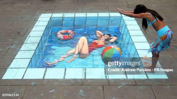 Miss England Danielle Llloyd dips her feet in the water with a 3D illusion of a swimming pool by pavement artist Julian Beever.