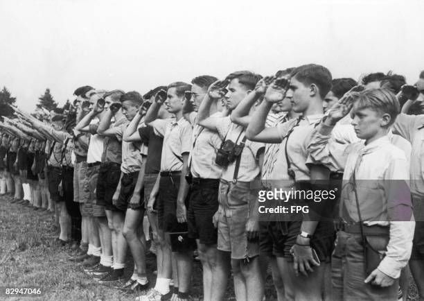 Members of a visiting American youth organization, along with members of the Hitler Youth , give their respective salutes at a flag-raising ceremony...