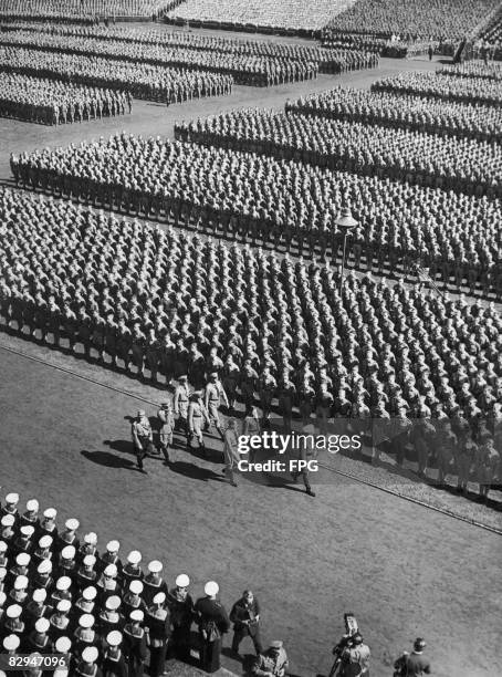 German Nazi leader Adolf Hitler reviews Hitler Youth formations at a Nuremberg Rally, circa 1935. Immediately behind Hitler are Rudolf Hess and...