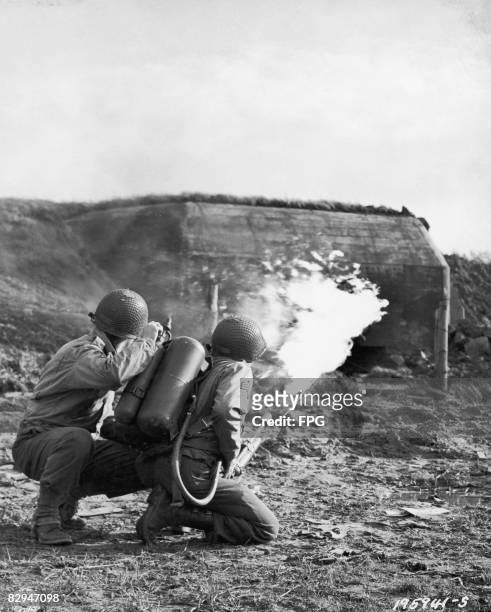 Servicemen Ashley L. Petit and William P. Loveland make a 'dry run' with a flamethrower on a German pillbox north of Aachen, Germany, 11th May 1944....