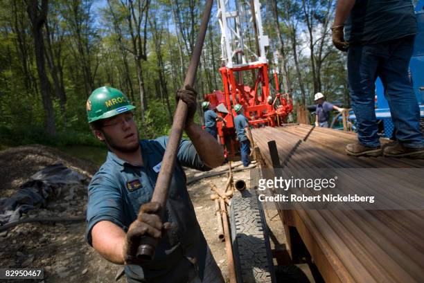 Minard Run Oil Company drilling team removes steel pipe sections from a recently drilled gas well whose side walls were notched before a high...