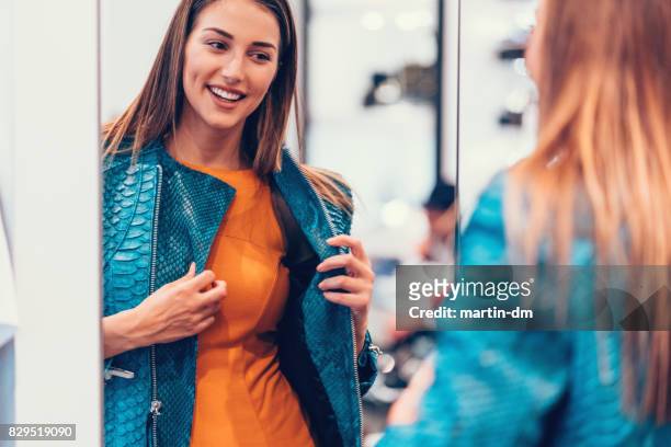 junge frau in der shopping mall genießen eine lederjacke - fashion boutique stock-fotos und bilder