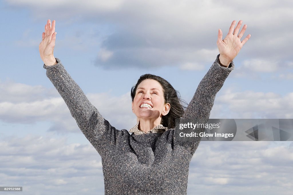 Close-up of a mature woman smiling with her arms raised