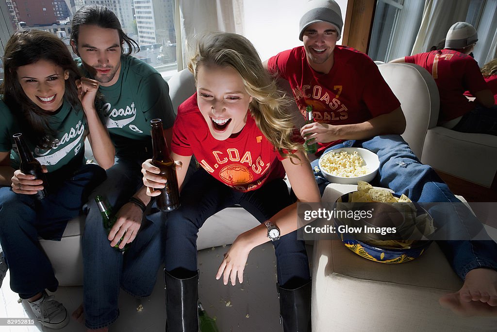 Two young couples sitting on a couch and drinking beer