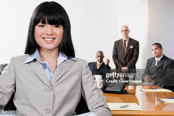 portrait of a businesswoman smiling with her colleagues in the background - portrait man suit smiling light background stock pictures, royalty-free photos & images