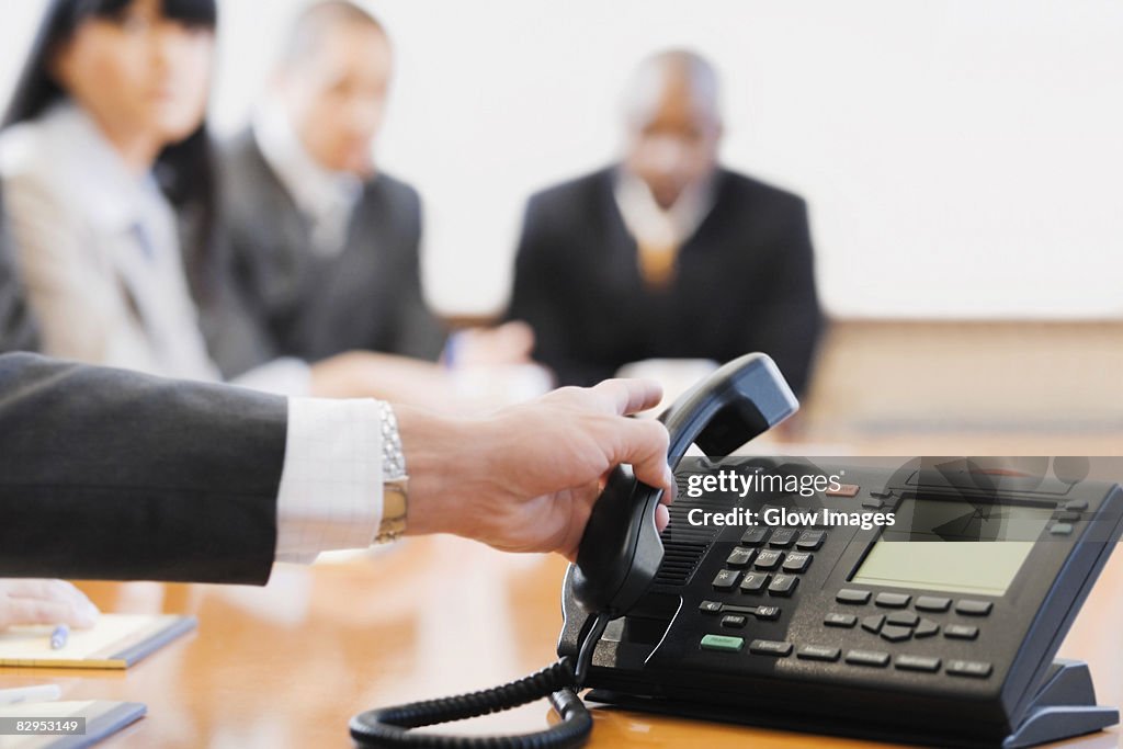 Close-up of a businessman's hand holding a conference phone receiver